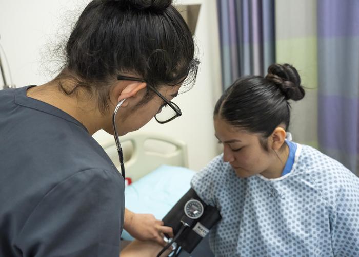 A female nursing assistant takes a female patient's blood pressure.